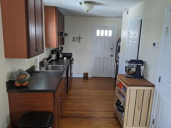 Kitchen w/ large cabinets, dishwasher, 1/2 bath, & backdoor leading to deck, yard, large bluestone patio & 2 reserved parking spots
