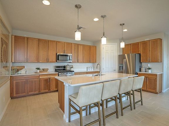 A spacious new kitchen with quartz island, stainless appliances, and a large corner pantry for optim