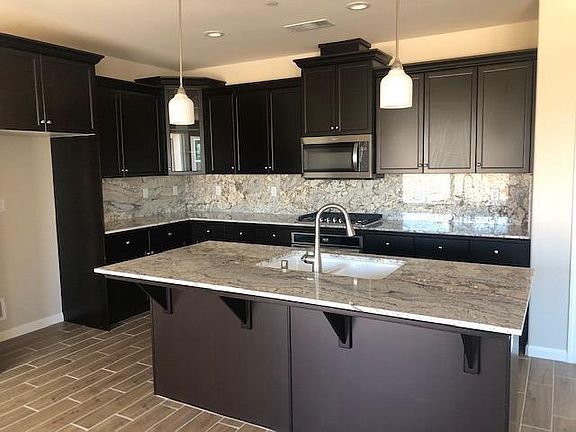 The kitchen features granite countertops and pendant lighting.