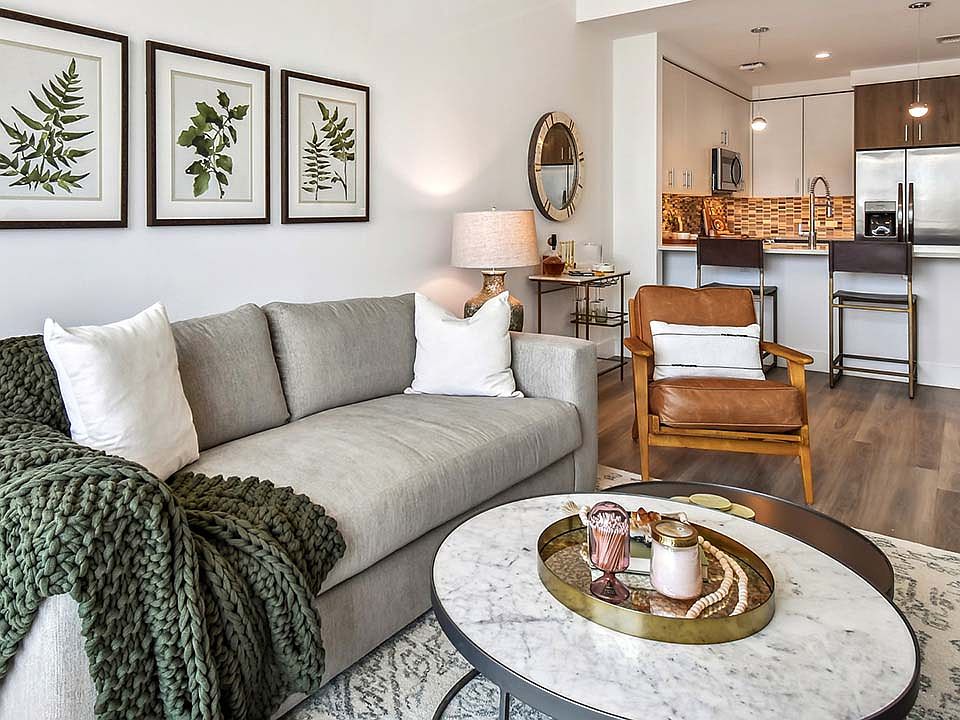 Griffis West Palm apartment living room with pattern rug, plush couch, framed artwork, and round tables.