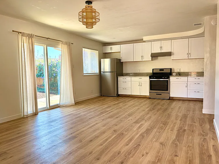 Front door leads into living area and kitchen, with sliding door leading into back yard