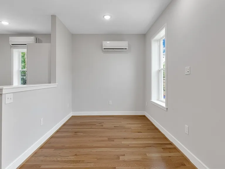 The living room has two large north-facing windows and is separated from the kitchen by a partition.
