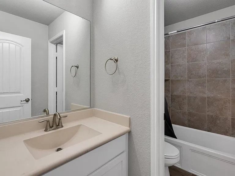 Bathroom featuring a single vanity with integrated sink, brushed nickel faucet, and frameless mirror