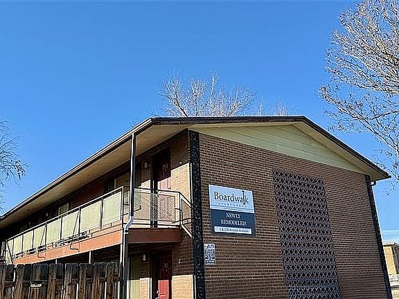 Charming newly remodeled brick apartment building with modern balcony and clear skies.