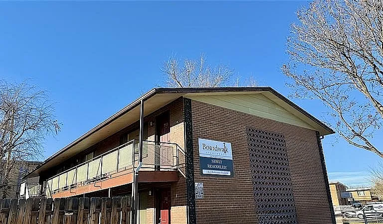 Charming newly remodeled brick apartment building with modern balcony and clear skies.