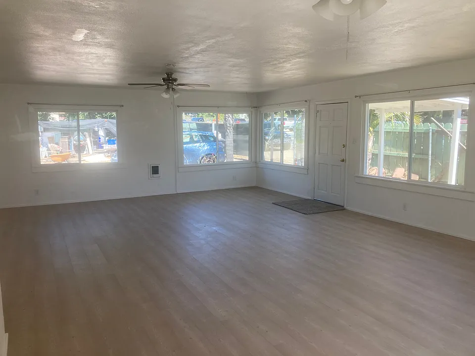 A view of the southwest corner of the combination living room/diniing room shows the recenlly laid flooring, new ceiling fans and numerous windows.