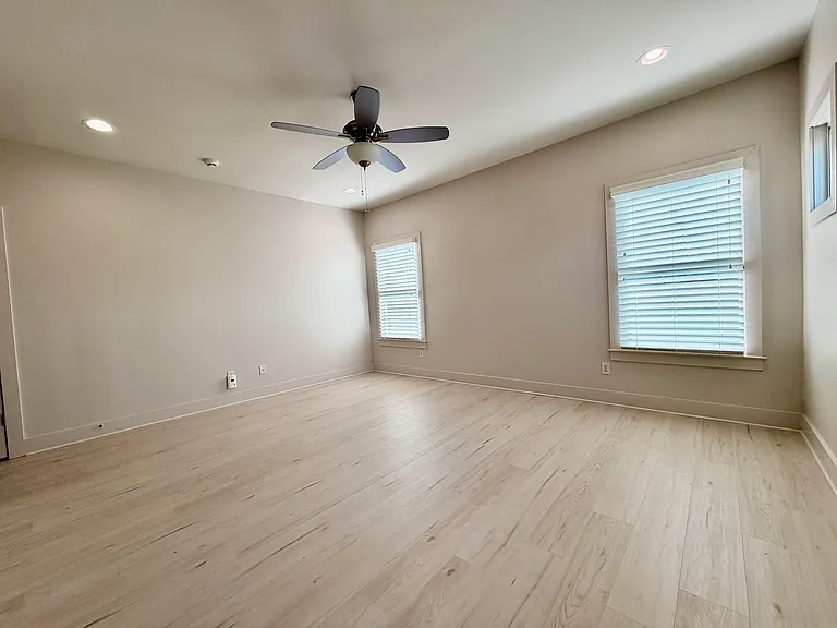 Windows overlook the backyard from the primary bedroom, and it also has a ceiling fan