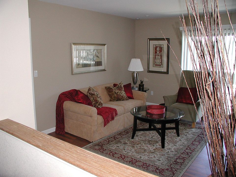 Front door opens in to open plan Living Room with recessed downlights and view of enclosed patio and locked private storage, through sliding door dressed with vertical blinds. View over wood-finished pony wall into combined dining room/kitchen.