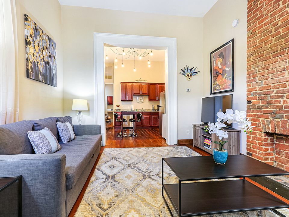 Large living room with 12-ft ceilings and exposed brick opens to a full kitchen