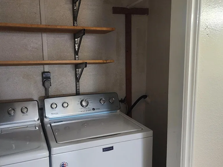 Side area next to washer and dryer for hanging clothes and storage.