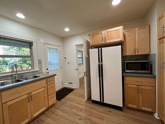 Plenty of storage cabinets in kitchen, view into shady serene backyard