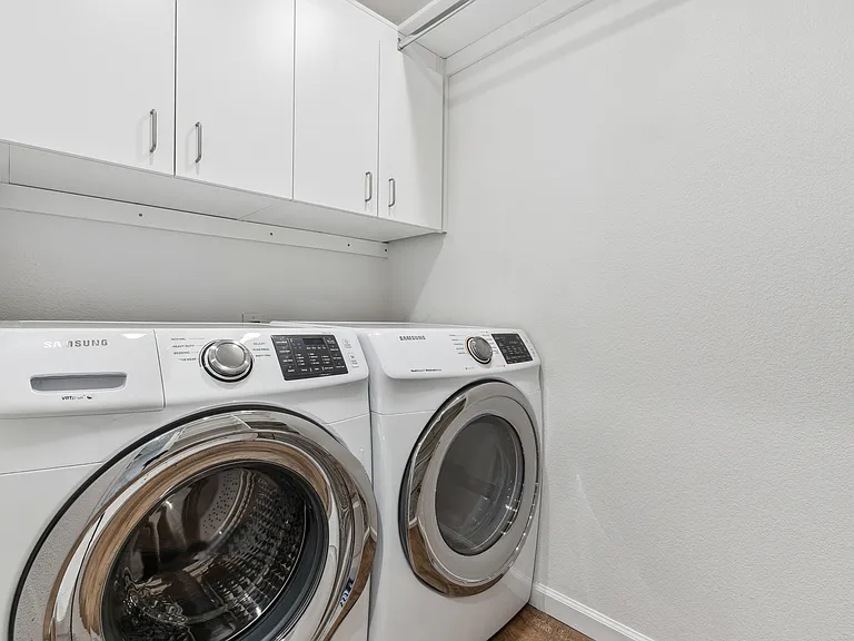 Laundry room with newer washer and dryer; customizable cabinets and storage. Hanging laundry bar.