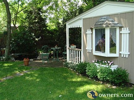 Dollhouse in yard in front of pond