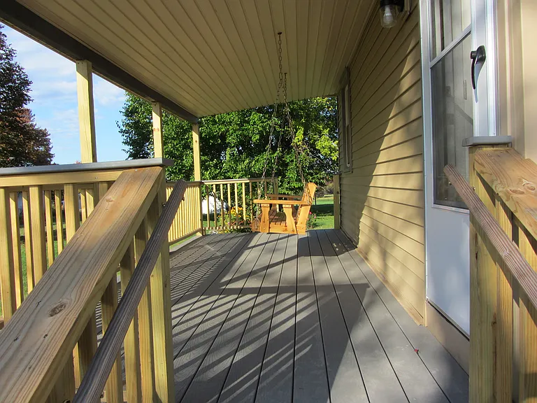 Newly constructed covered porch with wooden swing.