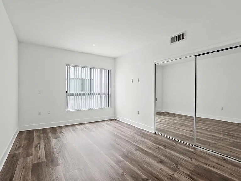 Bedroom with Mirrored Closet, Vinyl Flooring, and Windows