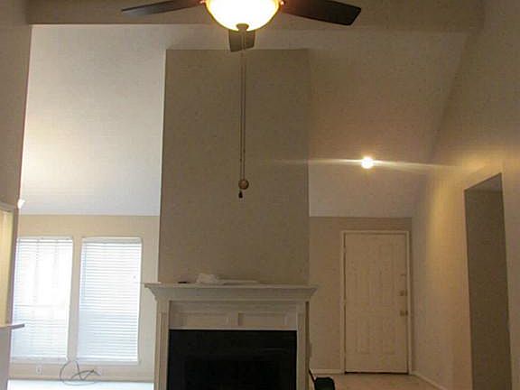 Large living room with vaulted ceiling, ceiling fan and fire