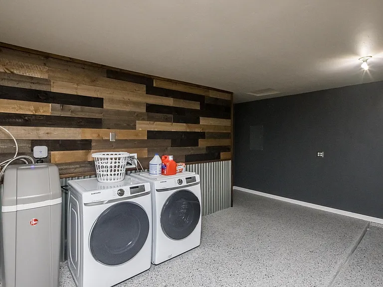Dedicated laundry space with washer and dryer, utility sink area, and custom accent wall for a clean, organized feel.