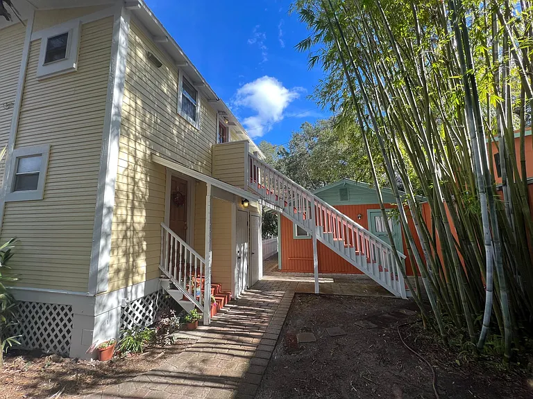 back yard with bamboo and sitting area. Leads to parking lot with pavers. Laundry is under the staircase.