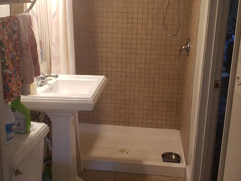 Second story bathroom that is connected to the front bedroom with pedestal sink and tile shower enclosure.
