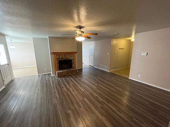 Living room with new floors, fireplace and access to kitchen.