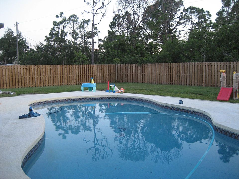 Kidney shaped pool with fenced in backyard.
