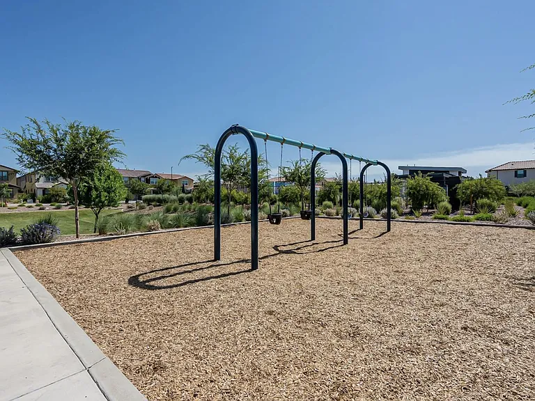 Community playground area with swing set, shaded landscaping, and nearby walking paths in a well-kept neighborhood.