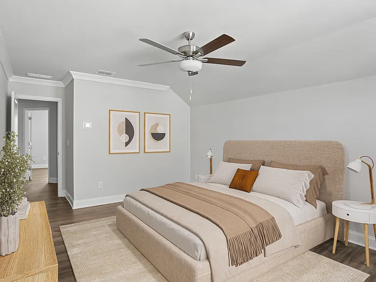 Primary bedroom with a plush bed, ceiling fan, and charming plant-accented table.