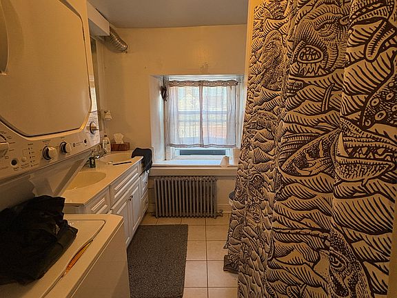 Bathroom with double sink, toilet, full shower and tub, and apartment gas washer and dryer.