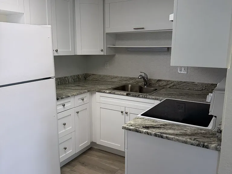 Several kitchen cabinets with granite countertops and flat-top range