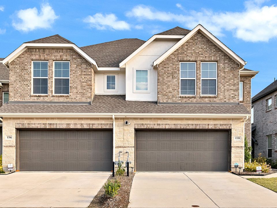 View of front of home with brick and stone siding, driveway, and 2-car garage