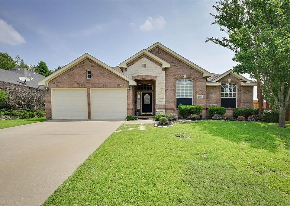 View of front of house featuring an attached garage, brick siding, a front yard, and concrete driveway