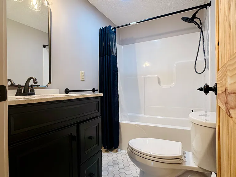 Second floor full bathroom with real marble hexagonal tile flooring, dark quartz vanity and full bathtub.