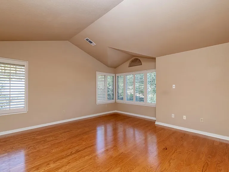 Primary bedroom vaulted ceilings and plantation shutters.