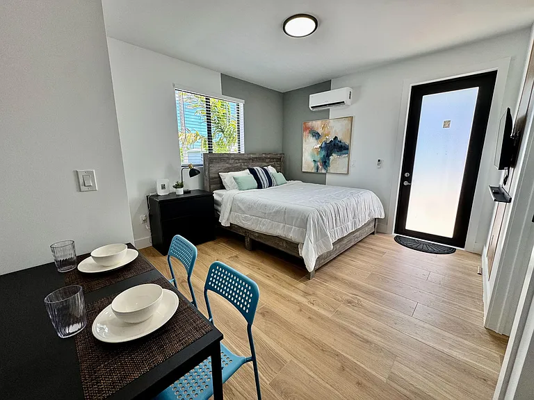 Furnished bedroom with a full bed, dresser, and mini-split A/C, plus a window and private exterior entry.