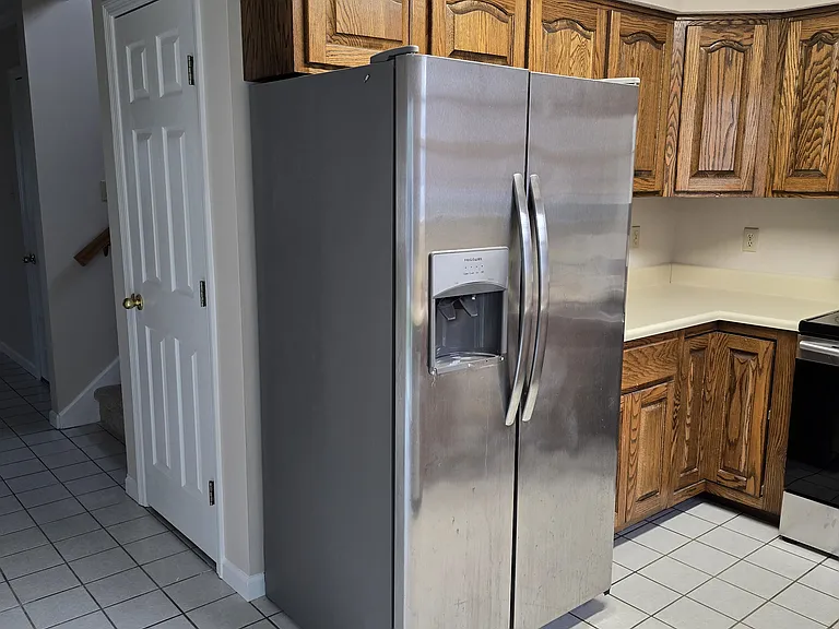Closet behind fridge is large storage area under the stairs.