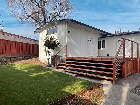 Backyard with newly installed artificial turf, draining, deck, gate, and lightning
