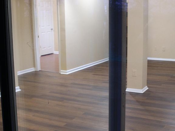 View of dining area closest to entrance, living room behind the pillar, and second bedroom/ office room in the distance to the left.