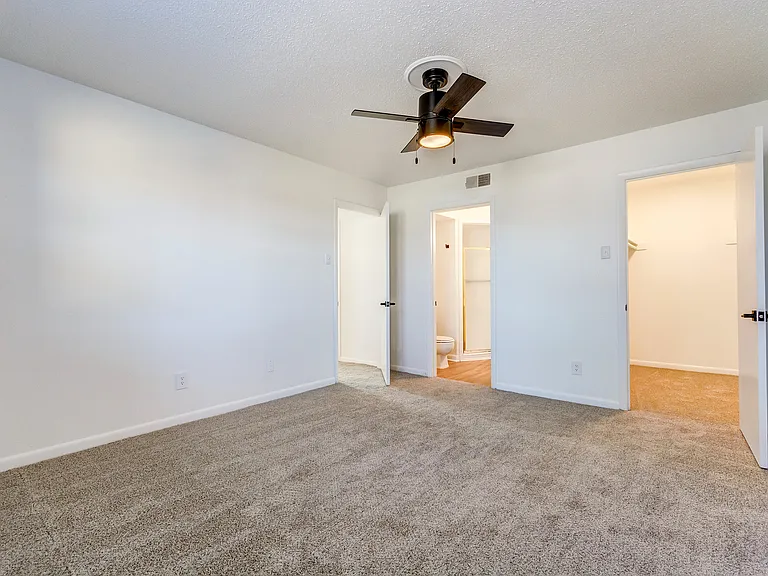 A carpeted bedroom with oversized closet and ceiling fan is shown at ReNew on Cantrell.