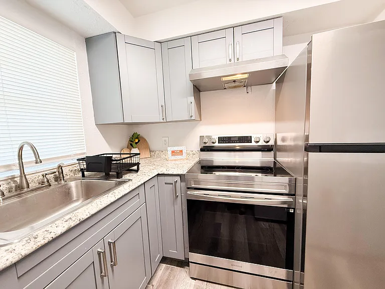 Updated kitchen with shaker-style cabinetry, granite-look counters, and stainless-steel range, hood, and refrigerator.