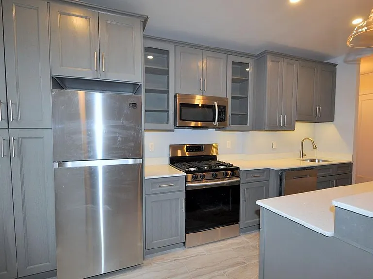 Renovated Kitchen with center Island, pendent lighting, Granite Counters, Stainless Steel Appliance including a dishwasher, range, microwave and refrigerator. The wall separating the eat-in-kitchen and living room have been removed and a center Island ins