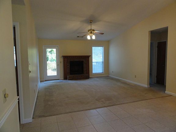 Vaulted great room with fire place and door to back yard. Hallway on right leads to 2nd and 3rd bedrooms.