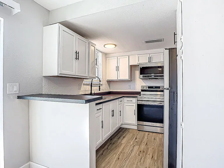 Modern kitchen with sleek white cabinets, stainless steel appliances, and wood flooring, creating a bright and inviting space. Modern kitchen with sleek white cabinets, stainless steel appliances, and wood flooring, creating a bright and inviting space.