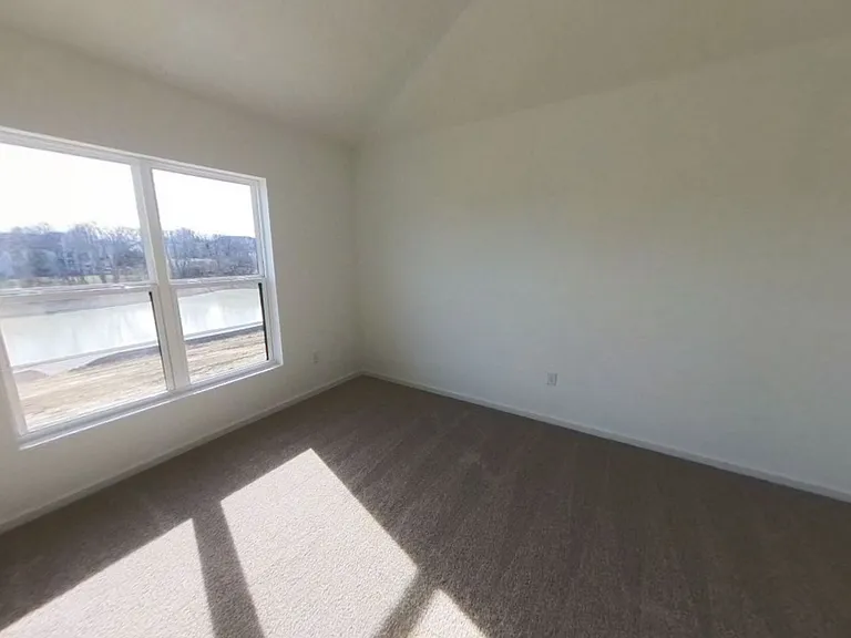 Master bedroom on main floor overlooking the pond and backyard. Vaulted ceiling.