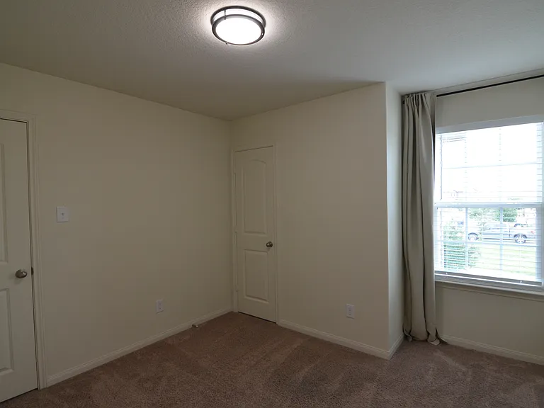 Secondary bedroom with natural light, closet space, and installed window coverings.