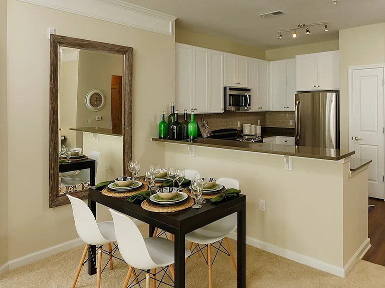 Dining area and kitchen with quartz stone countertop, white cabinetry, tile backsplash, stainless steel appliances and hard surface flooring