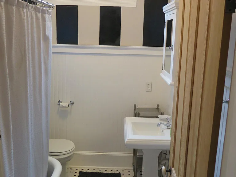Original clawfoot tub, pinwheel flooring and striped wall make up the stylish bathroom.