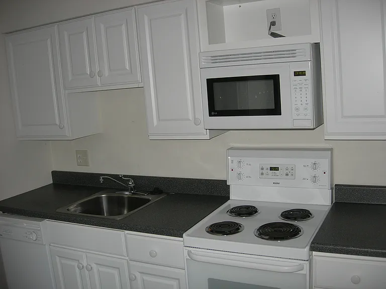 Modern, white, updated kitchen includes dishwasher, microwave, cooktop with oven, and refrigerator.