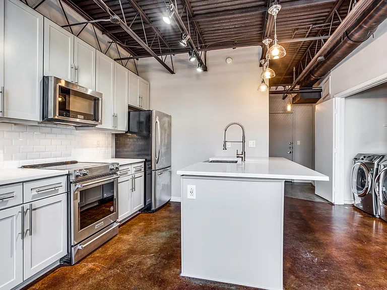 Kitchen with a center island with sink, backsplash, sink, washer and clothes dryer, and appliances with stainless steel finishes.