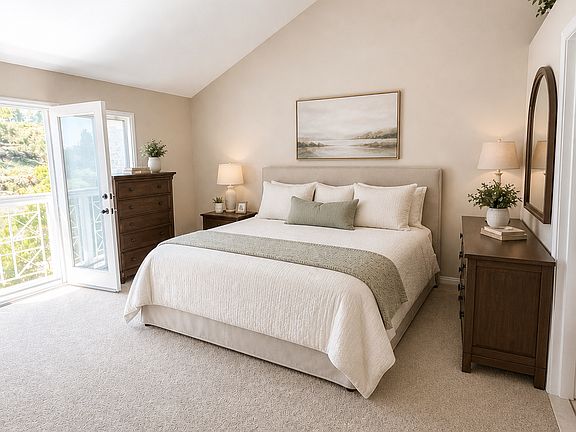 Master Bedroom - Spacious primary suite featuring French doors opening to a small private deck, new carpet, and abundant natural light. Enjoy a cozy fireplace, two walk-in closets, and a beautifully connected en-suite bathroom for comfort and convenience.
