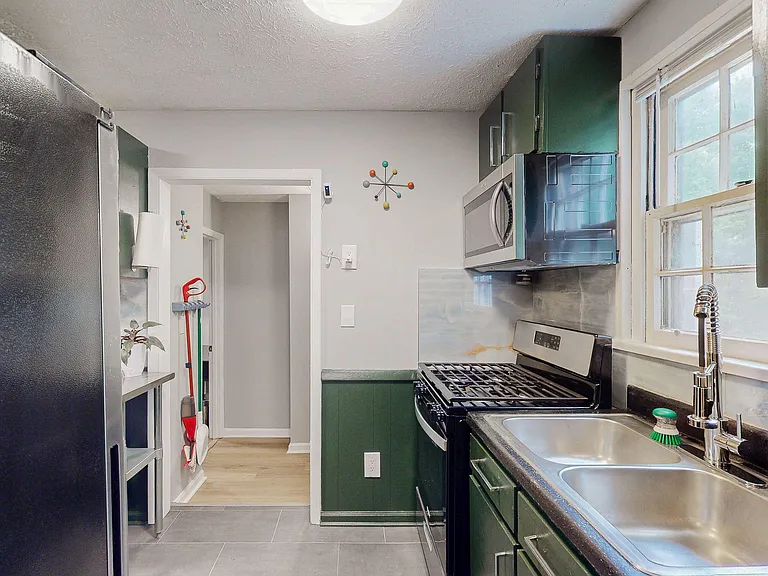 Galley kitchen with stainless appliances, double-basin sink, ample cabinetry, and a window over the counter for natural light